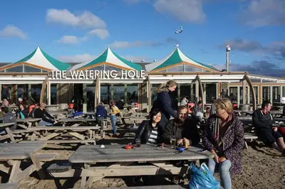 a group of people sitting at picnic tables in front of a building at Mellow Cottage just a short walk to the beach in Perranporth