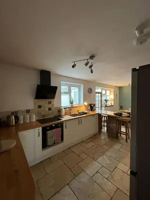 a large kitchen with white cabinets and a table at Mellow Cottage just a short walk to the beach in Perranporth