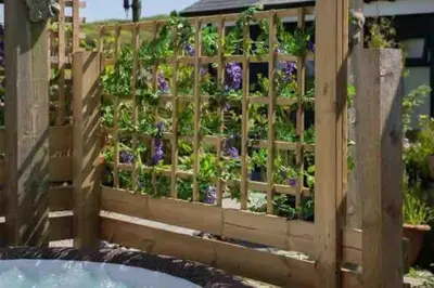 a wooden fence with purple flowers in a garden at The Stables in St Ives in St Ives