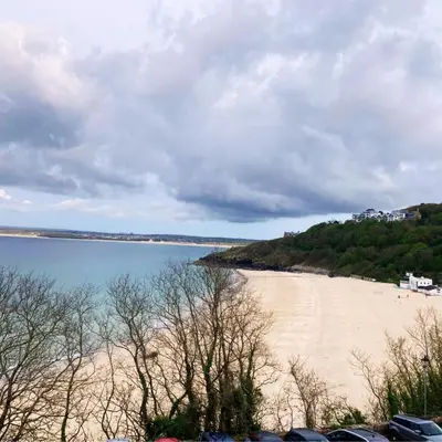 a beach with cars parked next to a body of water at The Stables in St Ives in St Ives