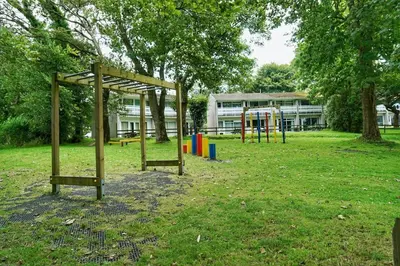 an empty park with a playground in front of a building at Special 2 Bedroom Home in White Cross in Saint Columb Major