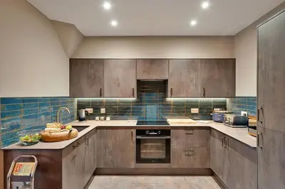 a kitchen with wooden cabinets and blue tile at Finest Retreats - Towan House in Newquay