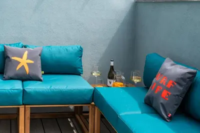 a blue couch with a table with wine glasses and wine bottles at Finest Retreats - Towan House in Newquay