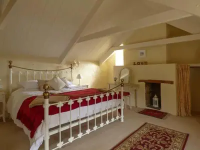 a bedroom with a large bed and a fireplace at Meadowside Cottage, Characterful Grade 2 Listed Cottage near to Wadebridge and Padstow in Wadebridge