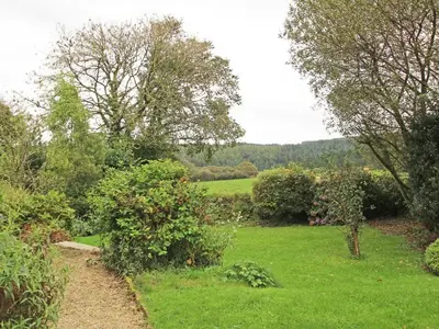 a garden with green grass and bushes and trees at Meadowside Cottage, Characterful Grade 2 Listed Cottage near to Wadebridge and Padstow in Wadebridge