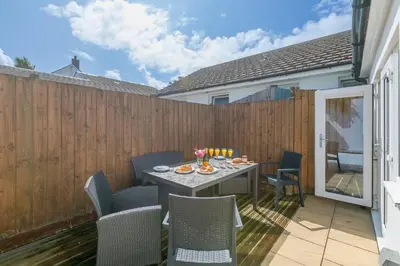 a patio with a table and chairs and a fence at Carvean in Carbis Bay