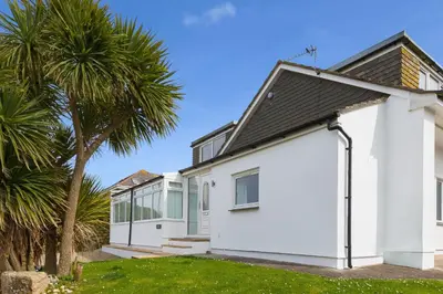 a white house with palm trees in front of it at Carvean in Carbis Bay
