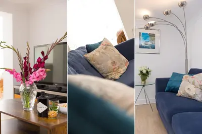 a living room with a blue couch and a table with flowers at Carvean in Carbis Bay