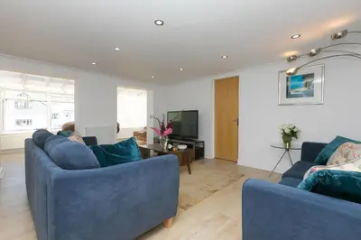 a living room with two blue couches and a television at Carvean in Carbis Bay