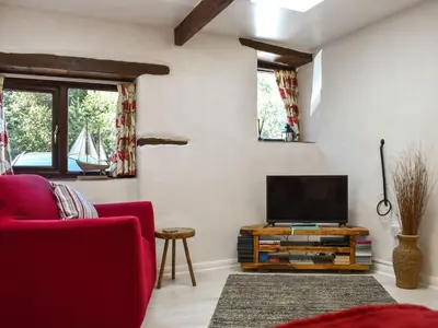 a living room with a red couch and a flat screen tv at Tarow Cottage in Morval