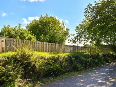 a wooden fence next to a road with trees at Tarow Cottage in Morval