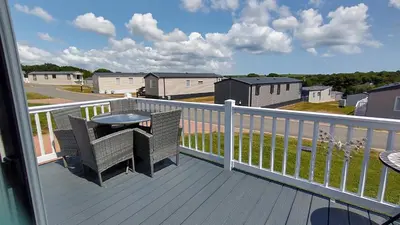 a balcony with a table and chairs on a deck at Roecliff in St Austell