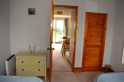 a bedroom with a door open to a room with a table at The Little House, Wadebridge, Cornwall in Wadebridge