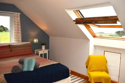 a bedroom with a bed and a yellow chair at The Little House, Wadebridge, Cornwall in Wadebridge