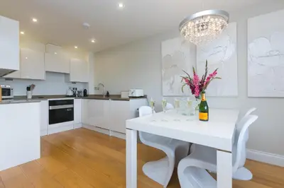 a white kitchen with a white table and white chairs at 2 Four Seasons in St Ives