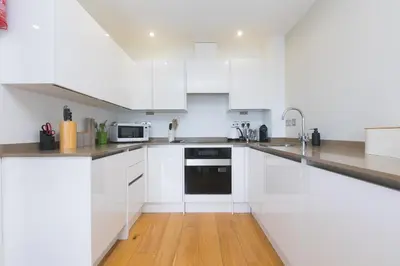 a white kitchen with white cabinets and a wooden floor at 2 Four Seasons in St Ives