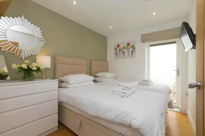 a bedroom with a white bed and a mirror at 2 Four Seasons in St Ives