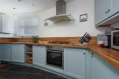 a kitchen with white cabinets and a stove top oven at Old Arch Cottage, The Digey - 100m From Town & Beach - Free WiFi - 2 Pets Allowed in St Ives