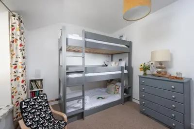 a bedroom with a bunk bed with a chair and a dresser at Old Arch Cottage, The Digey - 100m From Town & Beach - Free WiFi - 2 Pets Allowed in St Ives