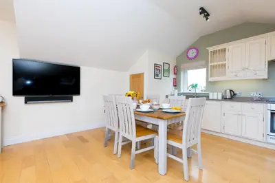 a kitchen with a table with chairs and a tv at 7 Sandy Lane in St Ives