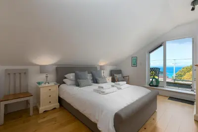 a bedroom with a large white bed and large windows at 7 Sandy Lane in St Ives