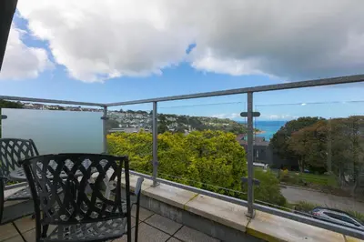 a chair on a balcony with a view of the ocean at 7 Sandy Lane in St Ives