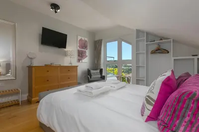 a bedroom with a large white bed with pink pillows at 7 Sandy Lane in St Ives