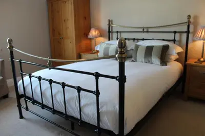 a bedroom with a large bed with white sheets and pillows at Camelot Guest House in Falmouth