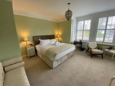 a bedroom with a bed and a couch and windows at Camelot Guest House in Falmouth