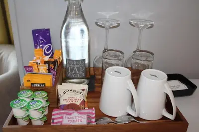 a table with two mugs and glasses and a bottle at Camelot Guest House in Falmouth
