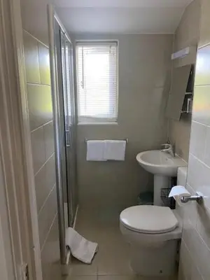 a white bathroom with a toilet and a sink at Camelot Guest House in Falmouth