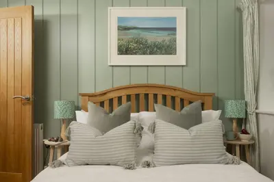 a bedroom with a bed with white sheets and pillows at Lobbs Cottage, St Mawgan - Free WiFi - Pet Friendly - Free Parking in Saint Mawgan