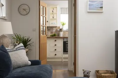 a living room with a blue couch and a kitchen at Lobbs Cottage, St Mawgan - Free WiFi - Pet Friendly - Free Parking in Saint Mawgan