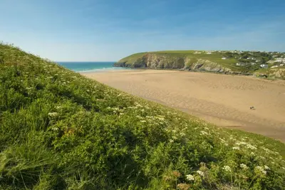 a grassy hill with a beach and the ocean at Lobbs Cottage, St Mawgan - Free WiFi - Pet Friendly - Free Parking in Saint Mawgan