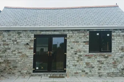 a brick building with black doors on it at New modern self contained Cottage in Delabole