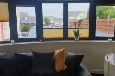 a couch sitting in a living room with three windows at New modern self contained Cottage in Delabole