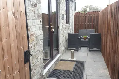a patio with two chairs and a table and a fence at New modern self contained Cottage in Delabole