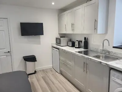 a small kitchen with white cabinets and a sink at The Cosy Nook in Redruth