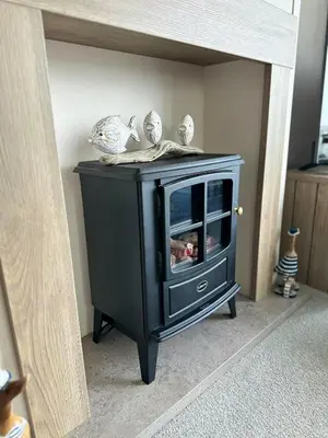 a black wood stove sitting in a room at Hot Tub Lodge Cornwall - Meadow Lakes Holiday Park in St Austell