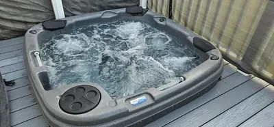 a jacuzzi tub with water in it on a deck at Hot Tub Lodge Cornwall - Meadow Lakes Holiday Park in St Austell