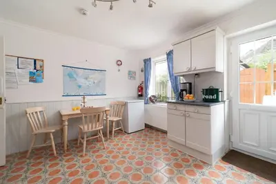 a kitchen with a table and chairs and a table and a counter at Seagulls Cottage Cornwall in Saint Mawes