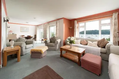 a living room with couches and tables and windows at Seagulls Cottage Cornwall in Saint Mawes