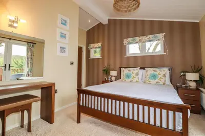 a bedroom with a bed and a desk and windows at Hideaway Lodge in Tintagel
