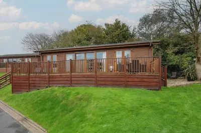 a large wooden house with a large deck at Hideaway Lodge in Tintagel
