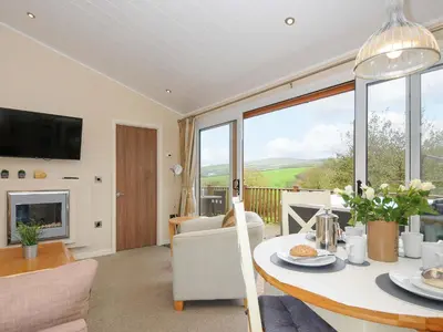 a living room with a table and a fireplace at Hideaway Lodge in Tintagel