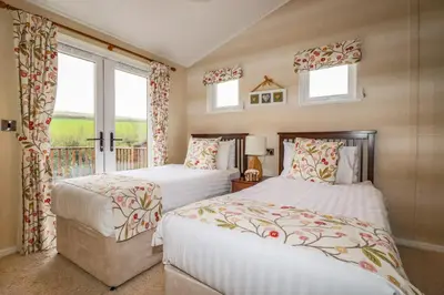 two beds in a room with two windows at Hideaway Lodge in Tintagel