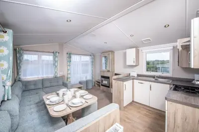 a living room and kitchen with a couch and a table at Killigarth Manor Holiday Park in Polperro