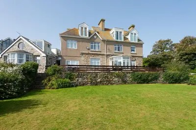 a large house with a stone wall and a yard at Shearwater View, 7 Rosemorran, St Ives in St Ives