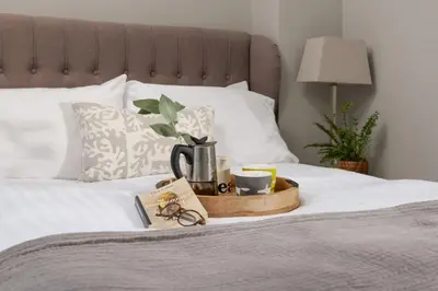 a tray with a coffee maker and cups on a bed at Shearwater View, 7 Rosemorran, St Ives in St Ives