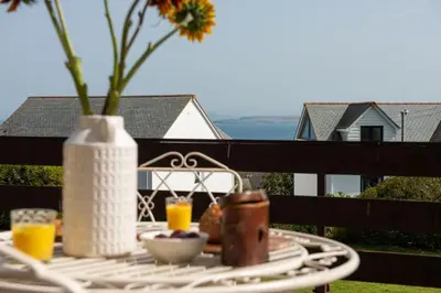 a table with a vase and drinks on a balcony at Shearwater View, 7 Rosemorran, St Ives in St Ives